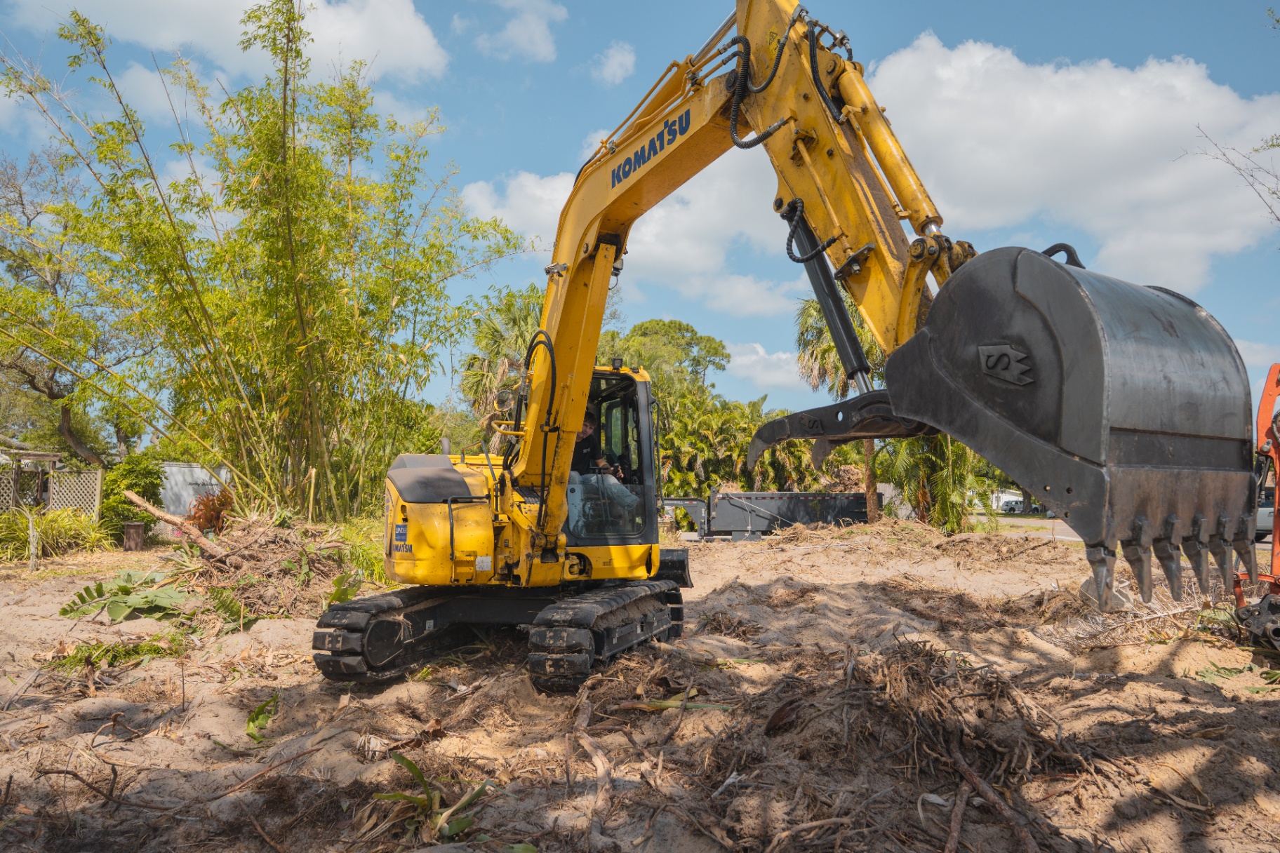 Komatsu excavator with heavy bucket on cleared sandy lot