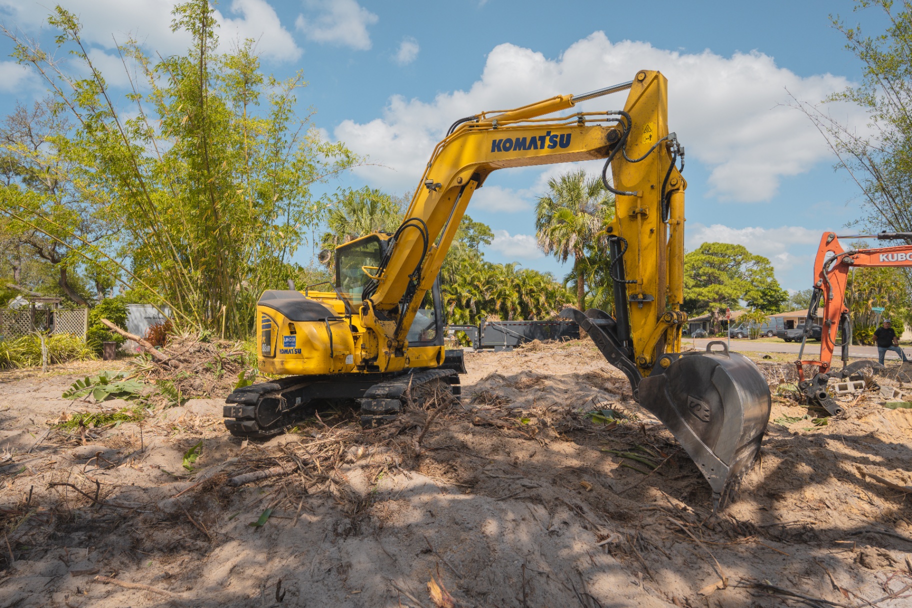 Komatsu excavator staged on cleared lot during site work